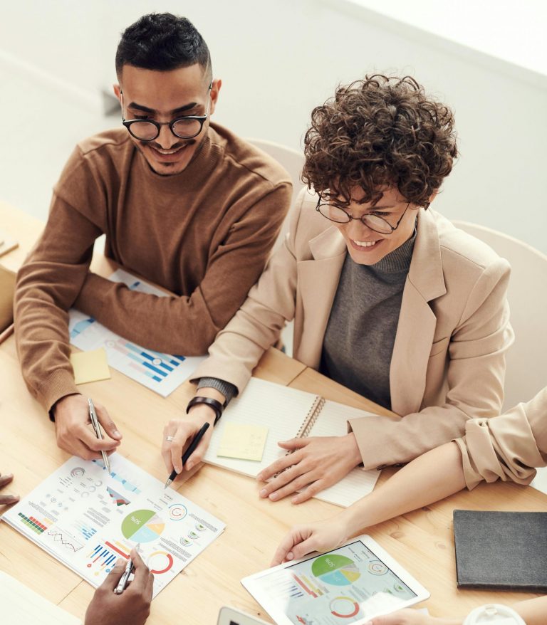 A diverse team of professionals collaborating over charts and graphs during a business meeting.